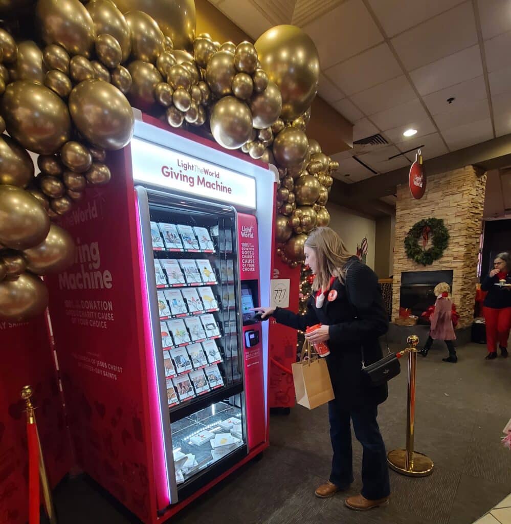 Woman making donation at Giving Machine in Westroads Mall for Light the World