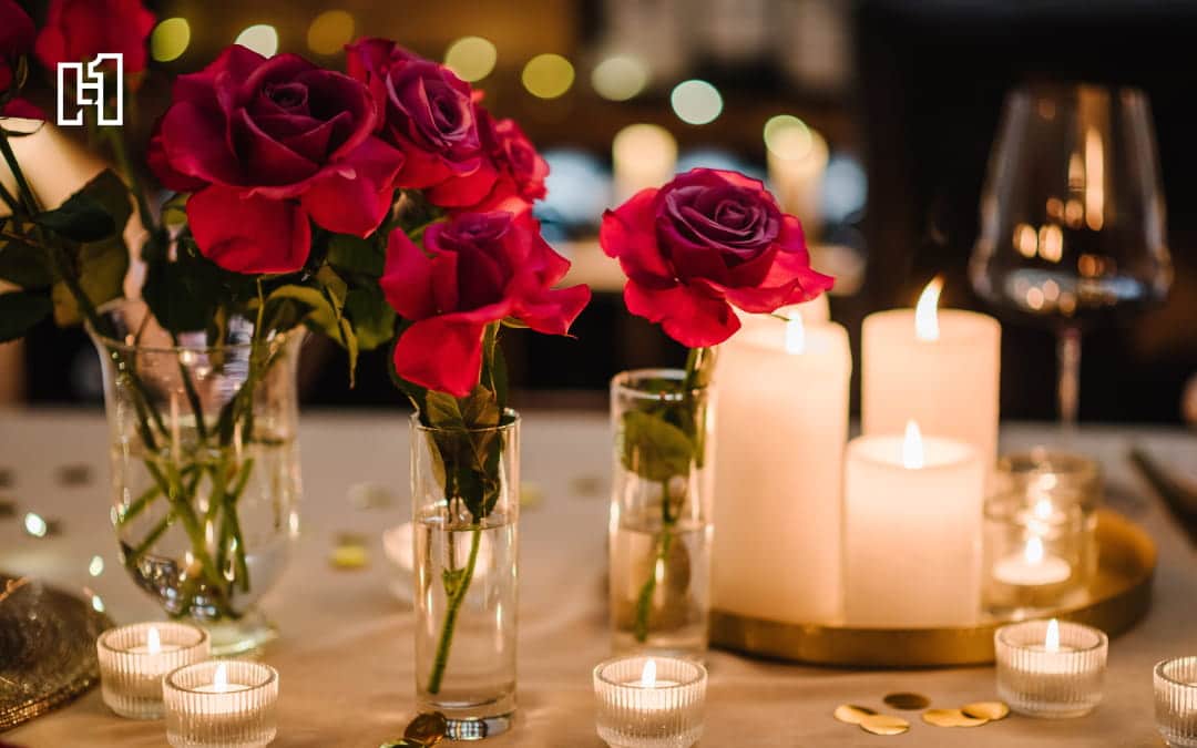 A close-up of a romantic dinner with roses and lit candles.